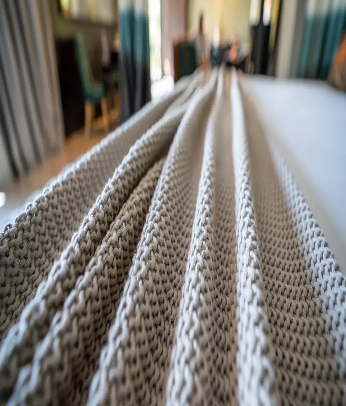 The image features a close-up of a knitted blanket draped over a bed in a stylish lodge room, with a softly blurred background suggesting a cozy interior.